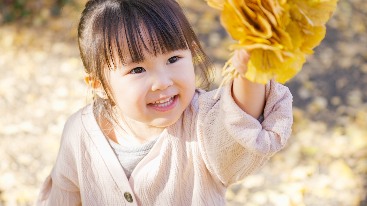 A young girl picks up leaves on a nature walk to build aesthetic awareness.