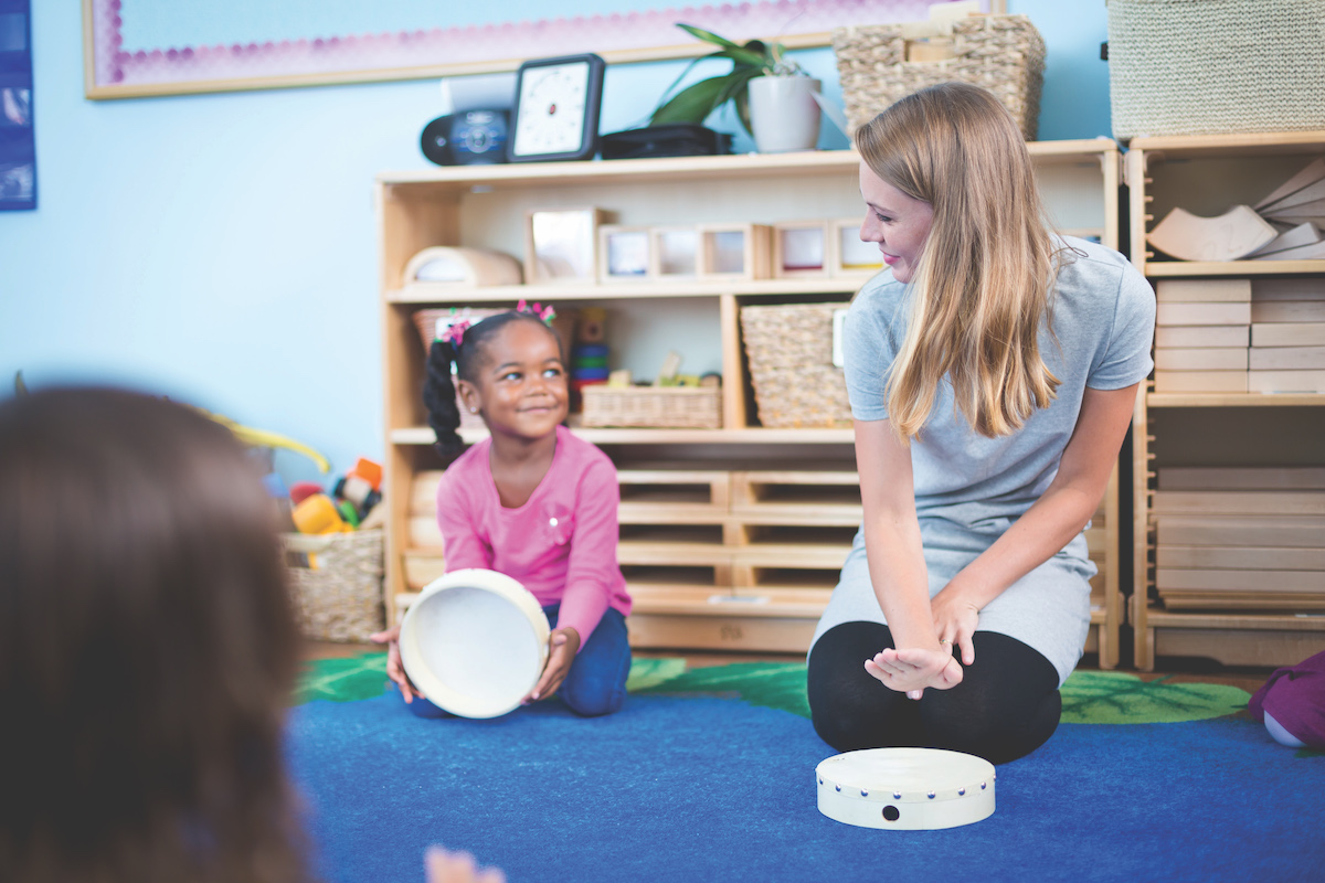 A teacher engages her preschool class in mimicking drum taps to test steady beat competency.