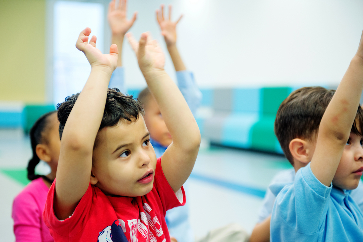 A multilingual learner sings with hand motions during a Kindermusik class.