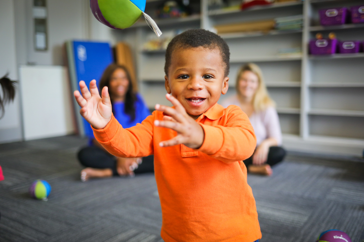 Young toddler throws a Kindermusik chime ball in class.