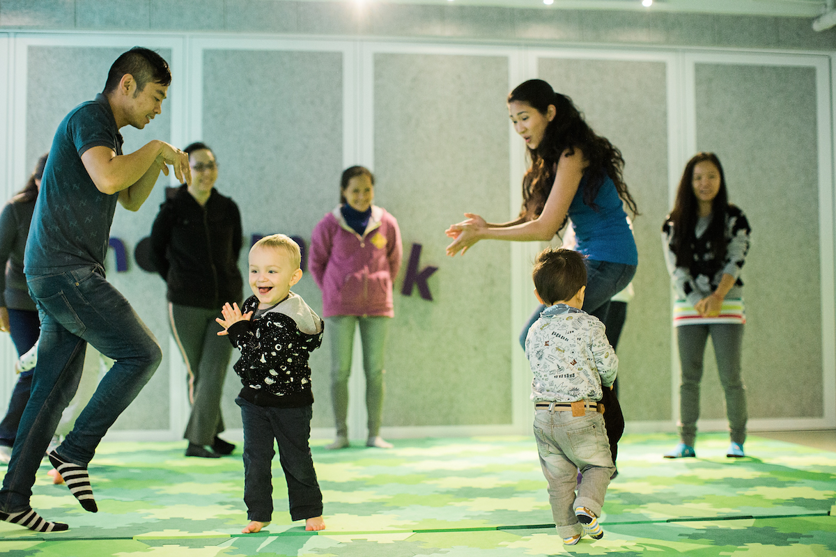 Toddlers dance in a Kindermusik class. Dancing as an emotion bridging tool helps toddlers experience feelings with grownups and break them down together after the song is over. 