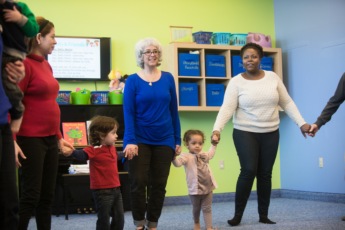 Families in a Kindermusik class participate in a circle dance. Dancing to the beat or in sync with your children are one of the easiest parenting resolutions to boost connection and empathy.
