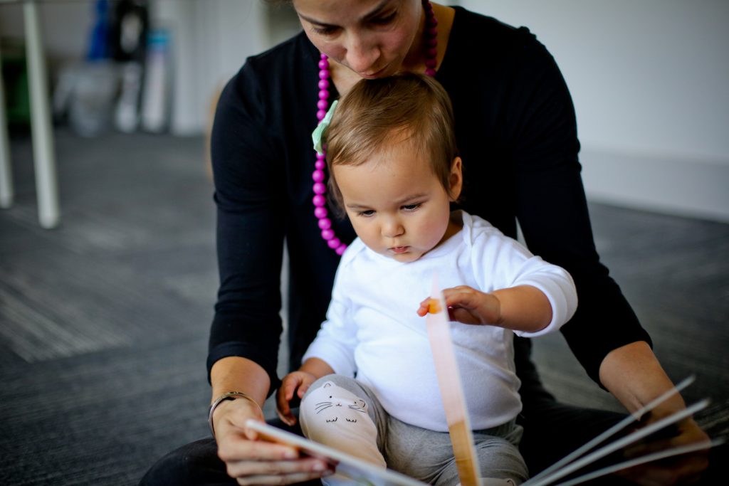 Mom and 10-month-old daughter reading a board book during Kindermusik class.