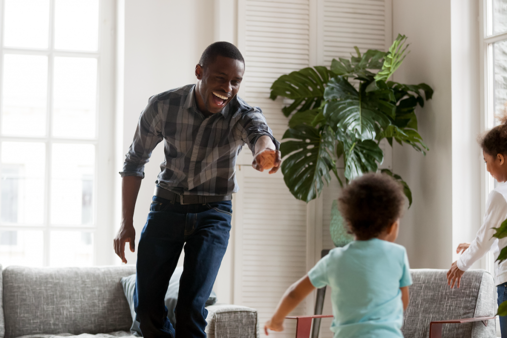 A dad dances with his kids at home. Sometimes, playing your favorite songs when your with your children is an easy way to keep parental social-emotional growth in check.