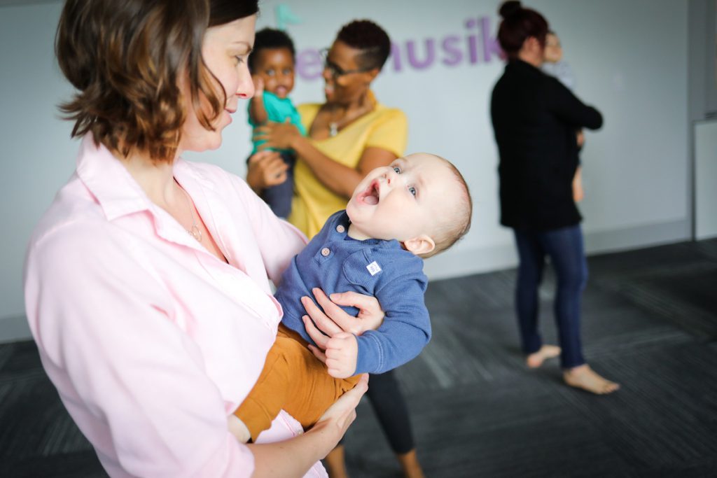 A baby mimics mom as she sings a high-pitched kid song in a Kindermusik class.