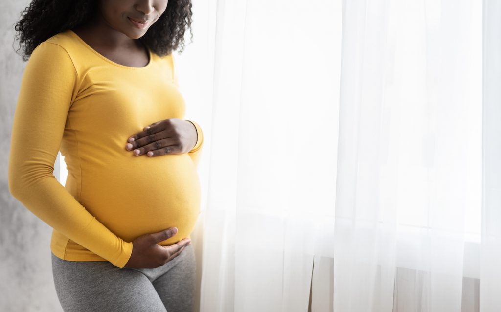 Pregnant mom holds her belly. Singing to baby in utero can promote secure attachment.