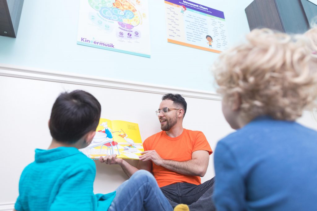 A Kindermusik teacher reads aloud a rhyming book in class. Rhymes are key to supporting phonemic awareness.