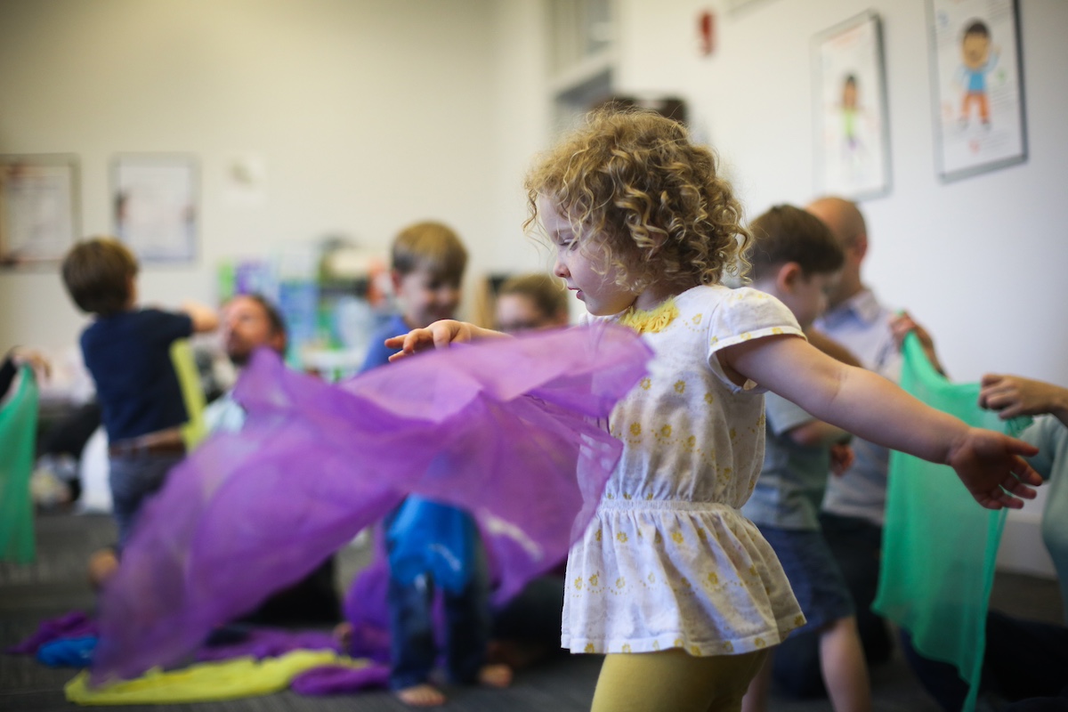 3-year-old girl twirls with scarf during a Kindermusik class to stimulate the vestibular system.