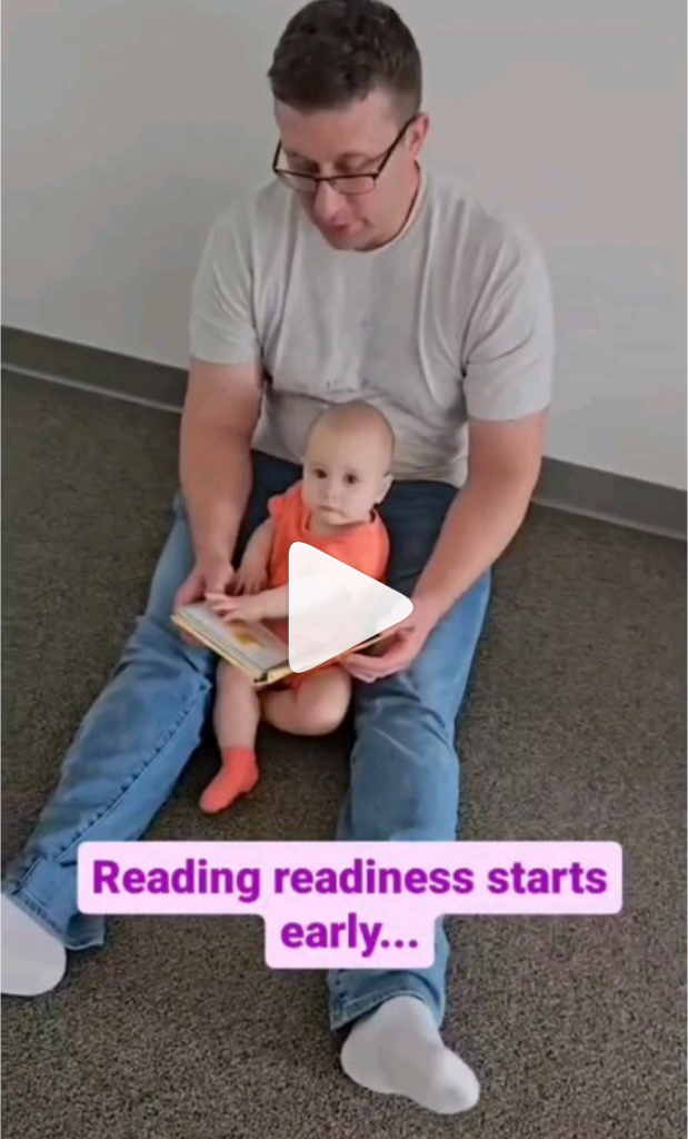 Dad reads aloud to baby on the floor during a Kindermusik class as instructor points out the benefits of serve and return. 