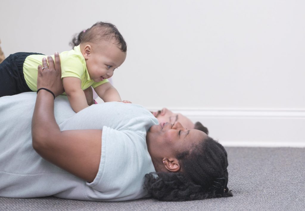 A mom plays serve and return with her 5-month old son while lying on the floor. 