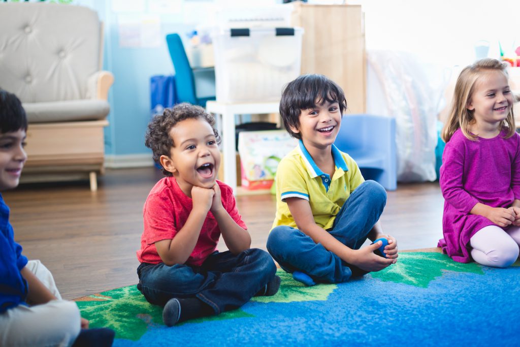 Preschoolers sing a Kindermusik song during circle time on the carpet; this group activity supports emotional intelligence.