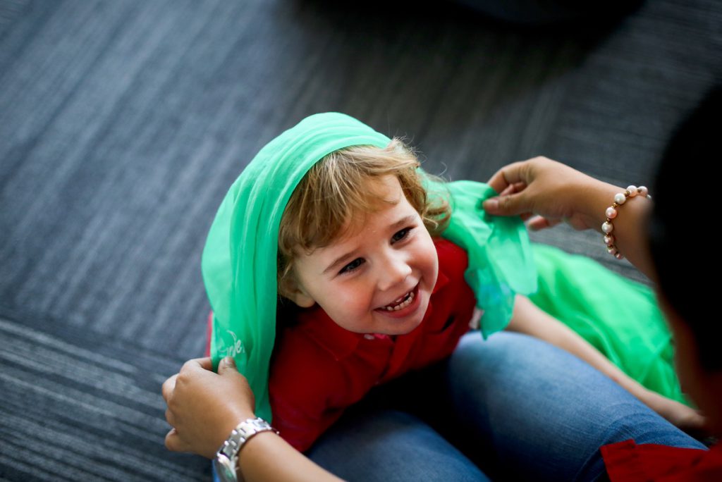 A 2-year-old boy plays peek-a-boo with his mother with a sheer scarf. This activity involves eye contact, trust, and other factors that support emotional intelligence development.